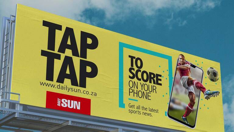 SIMONSAYS DIGITAL AGENCY Daily Sun. Bright yellow billboard promoting sports news, featuring a football player kicking a ball from a smartphone.
