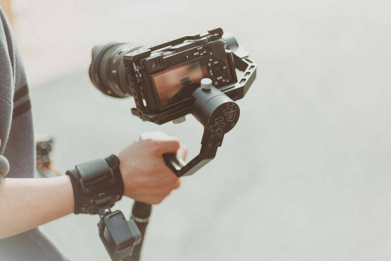 SIMONSAYS DIGITAL AGENCY Camera stabilizer held by a person, showcasing a compact camera and rig setup for smooth filming.